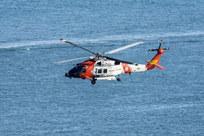 orange and white helicopter on body of water during daytime