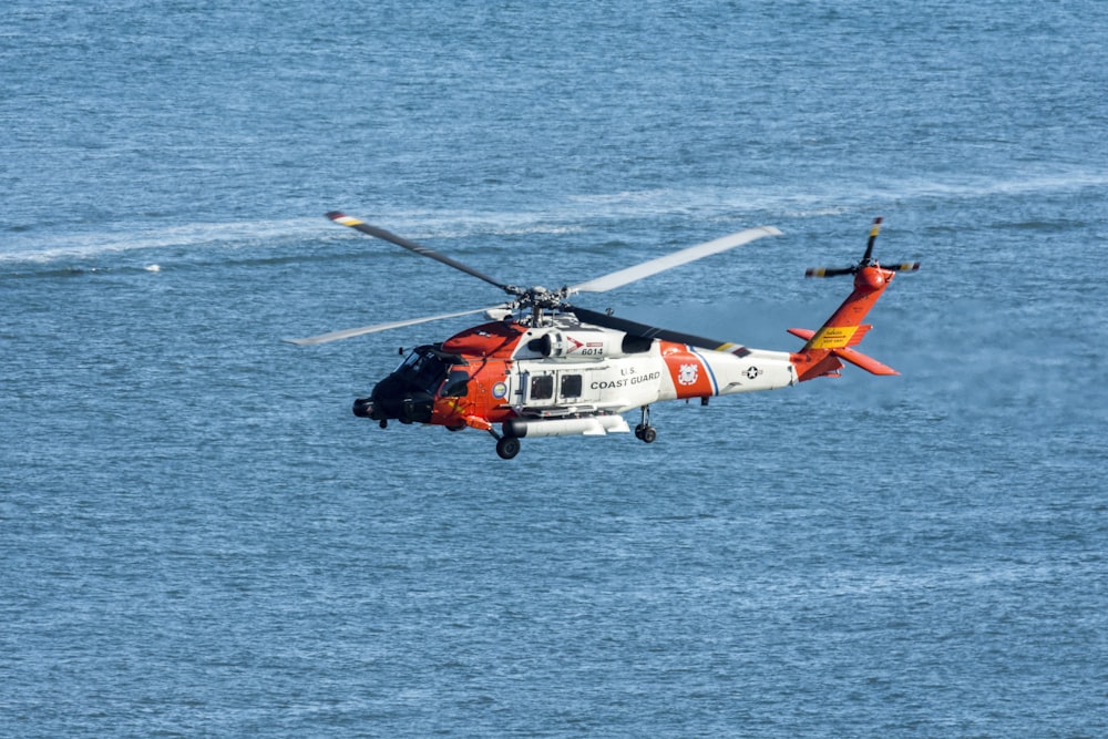 orange and white helicopter on body of water during daytime