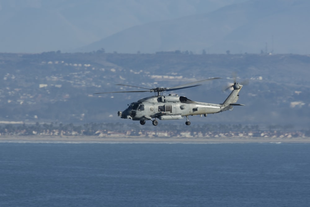 white and black helicopter flying over the sea during daytime