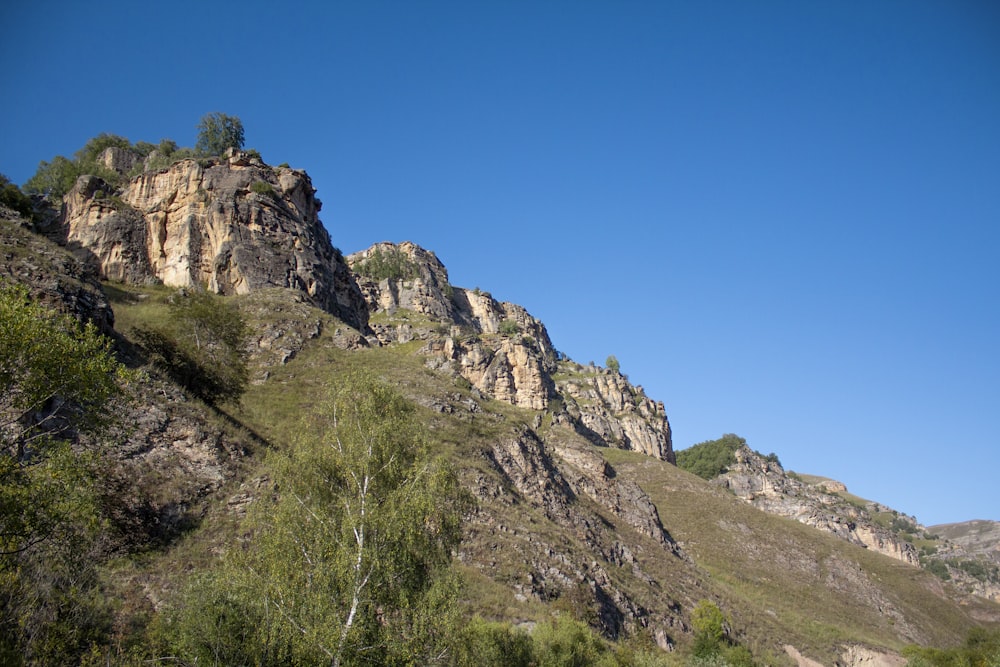 green grass on rocky mountain under blue sky during daytime