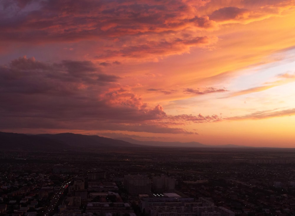 city skyline under orange and gray cloudy sky during sunset