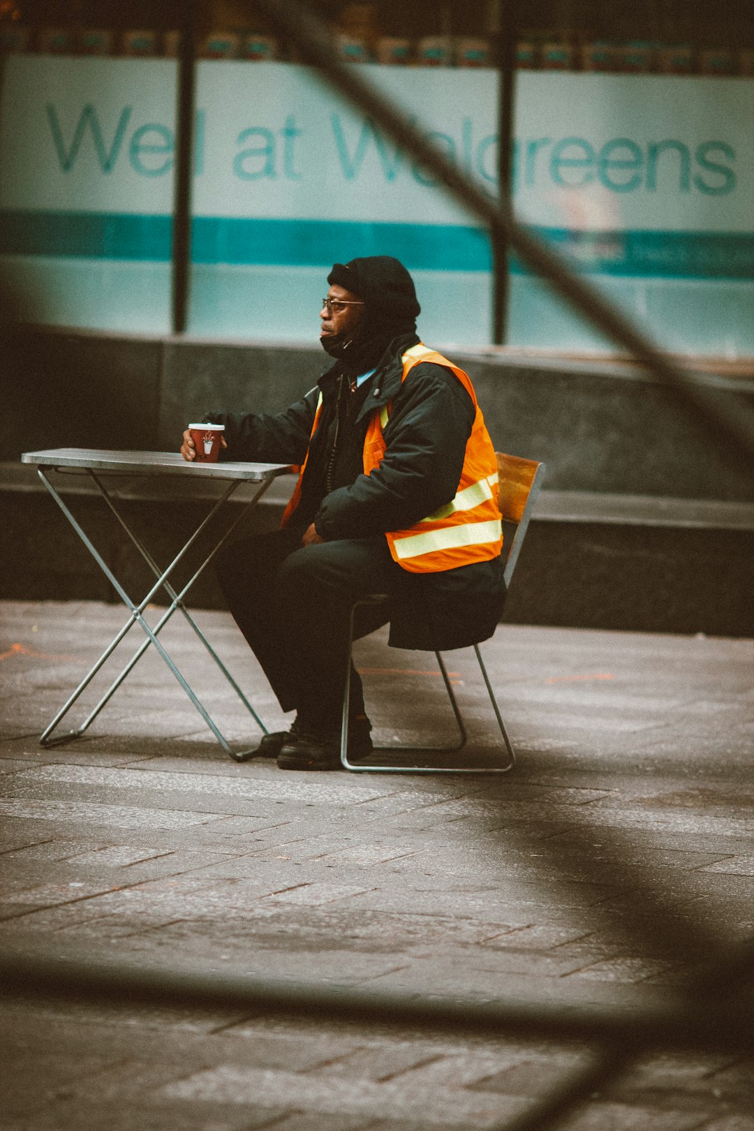 man in black and orange jacket sitting on chair