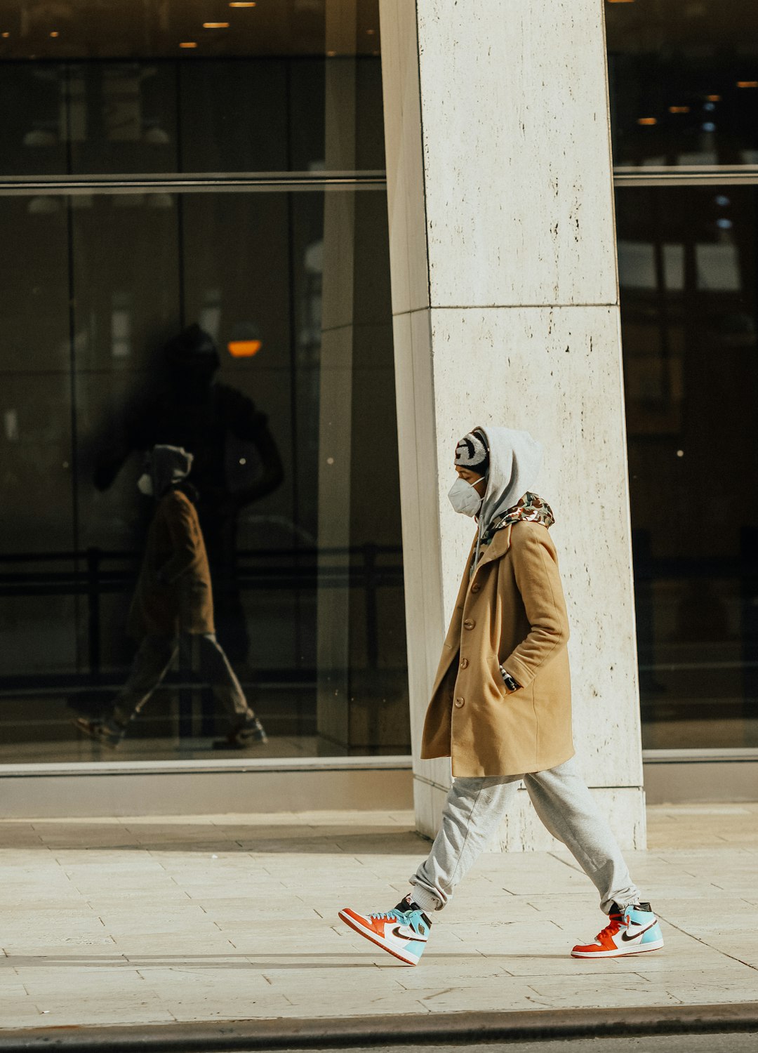 person in brown coat walking on sidewalk during daytime