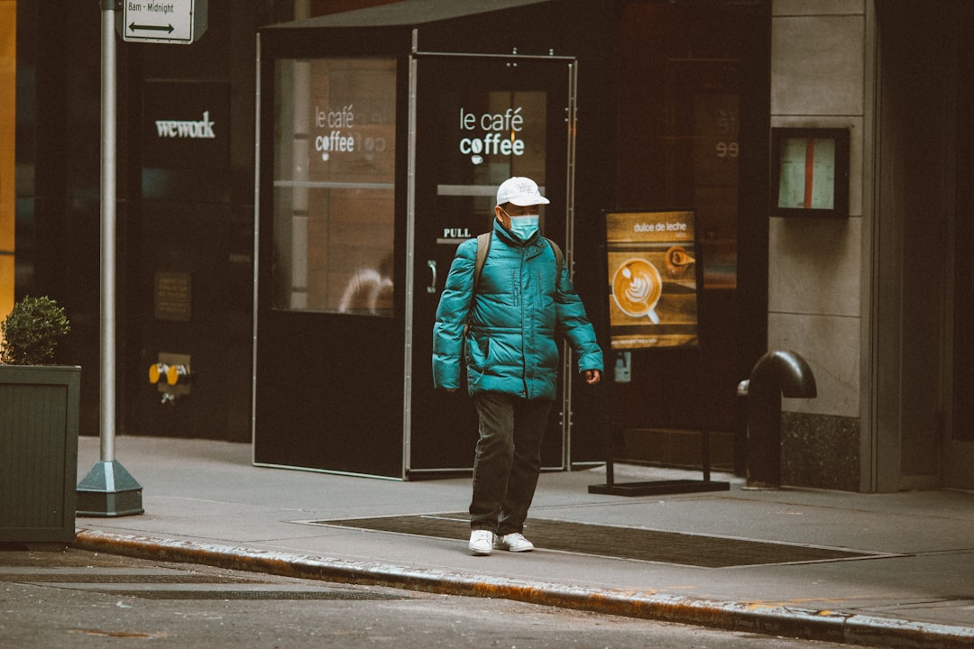 man in blue jacket and black pants standing near store