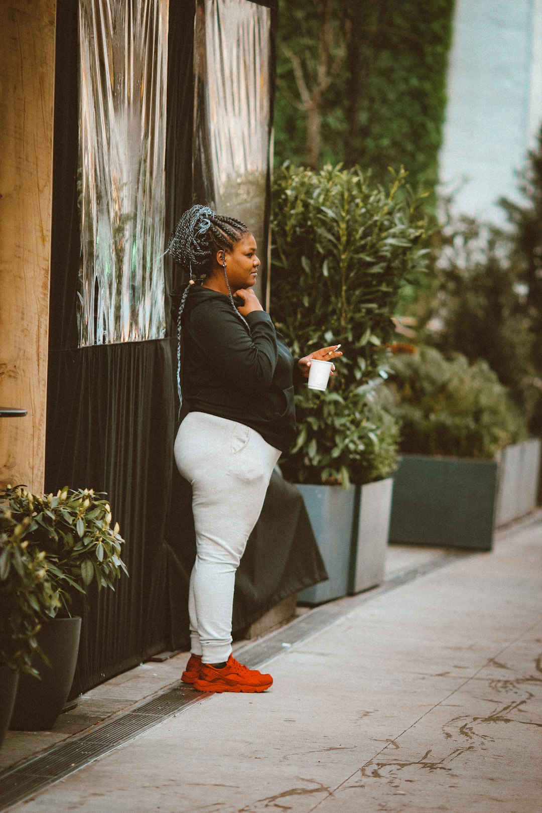 woman in black long sleeve shirt and white pants standing beside brown wooden wall during daytime