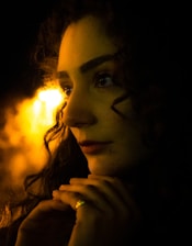 Professional portrait of Ruth Arrieta in a dark, elegant office setting with warm golden lighting.