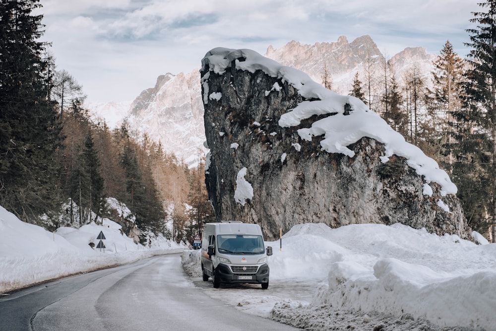 black car on road near mountain covered with snow during daytime