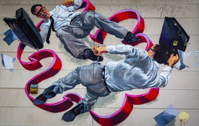 A mural depicts two men in business attire, with one appearing to have black hair and both wearing glasses. They are entangled and floating amidst swirling red ribbons and scattered papers, each holding a briefcase.