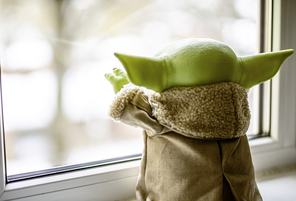 green frog plush toy on brown textile