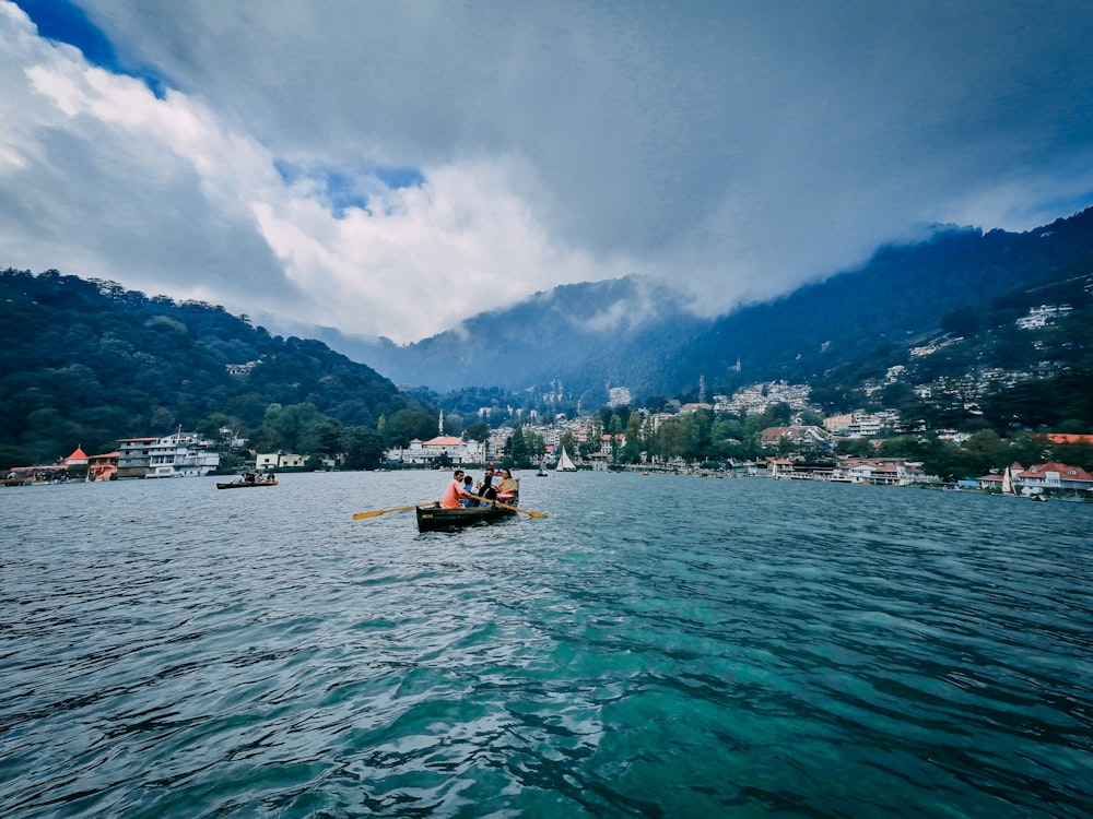 boat on sea near mountain under white clouds and blue sky during daytime