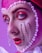 A close-up portrait showcases intricate makeup artistry, featuring vibrant red and pink eyeshadow, and striking red lipstick. Pearls and crystals delicately embellish the face, creating a theatrical and avant-garde style against a purple background.