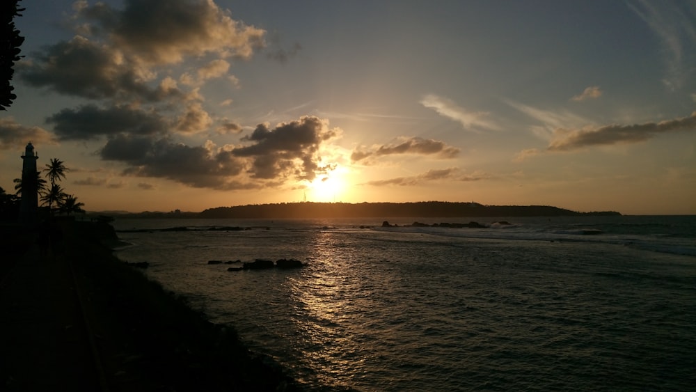 body of water under cloudy sky during sunset