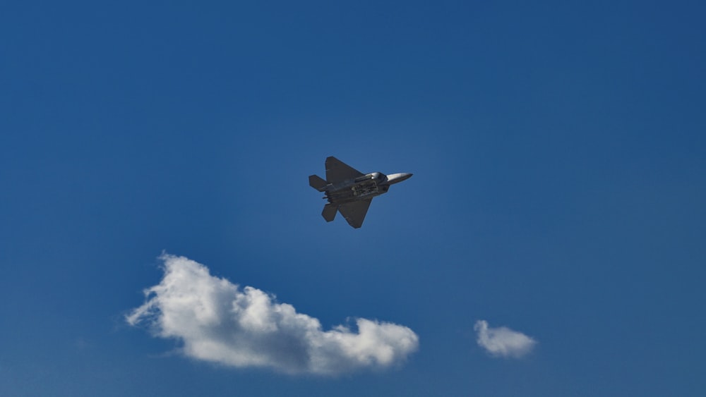 black jet plane in mid air under blue sky during daytime