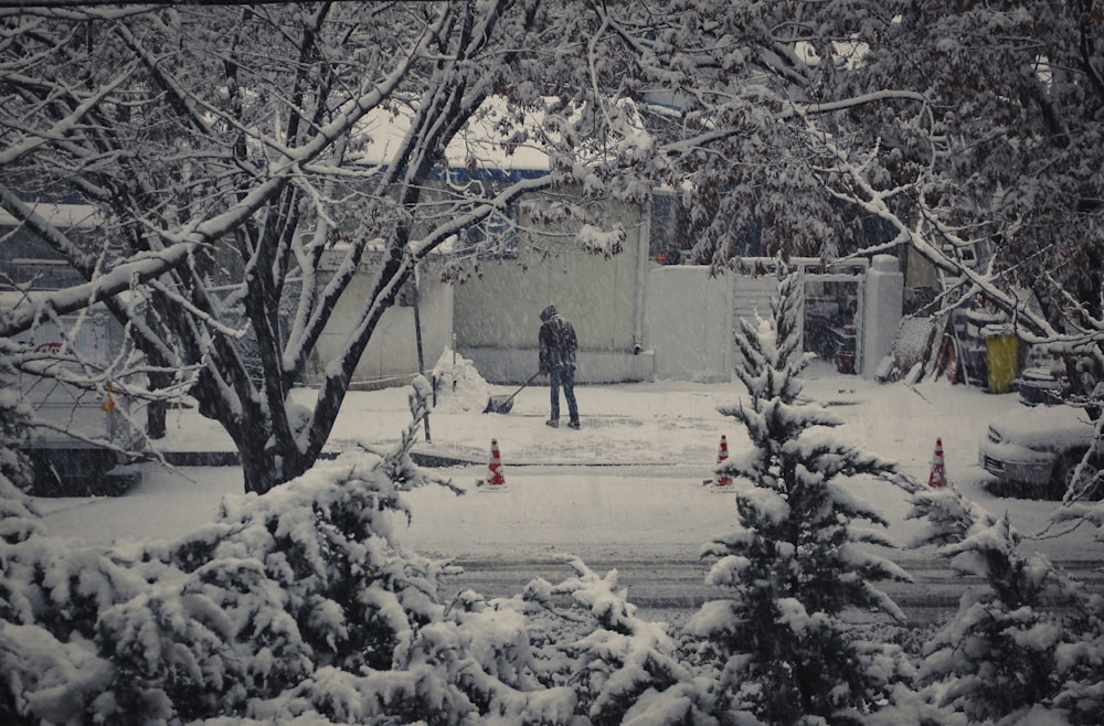 man in black jacket and blue denim jeans standing on snow covered ground