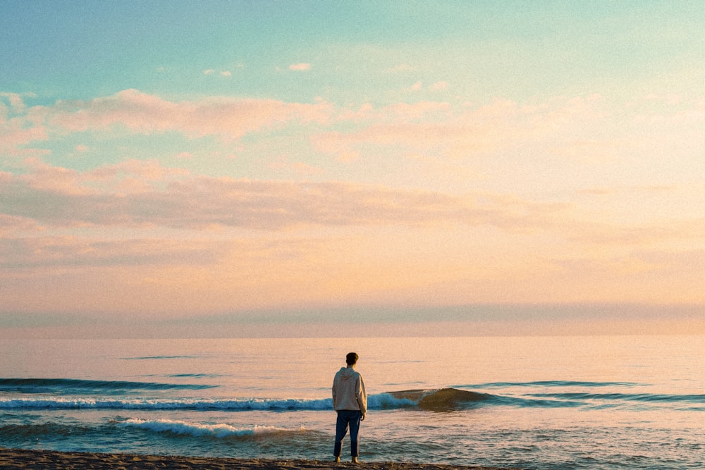man in white long sleeve shirt standing on seashore during daytime