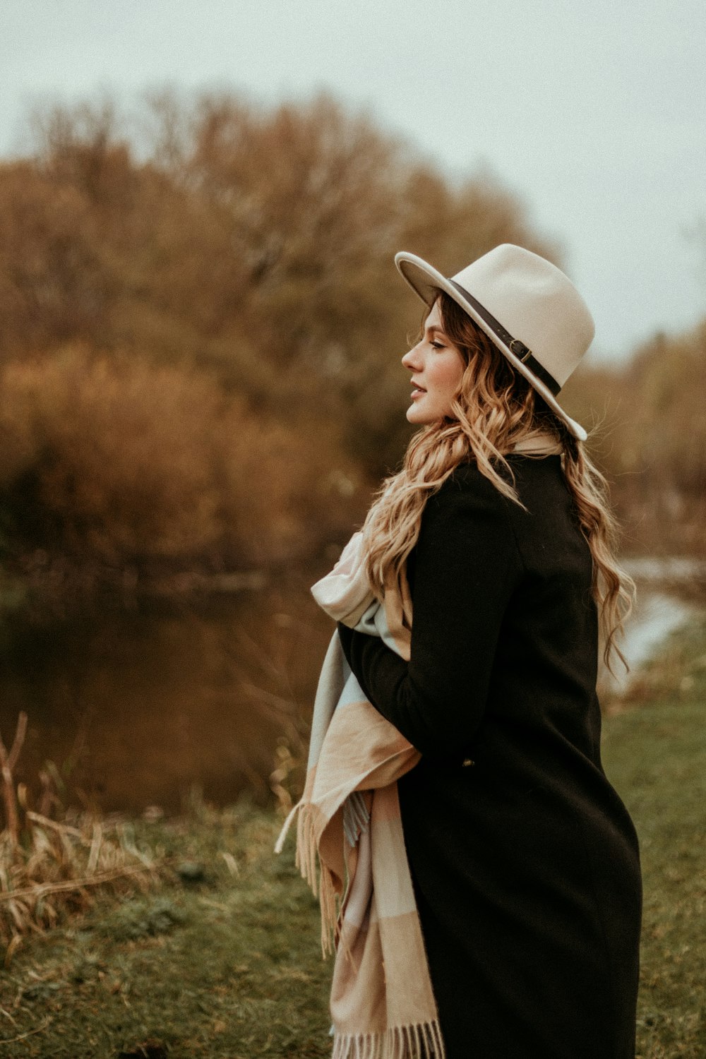woman in black coat and white sun hat standing on green grass field during daytime