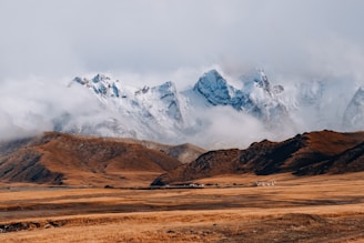 brown and white mountains under white clouds during daytime