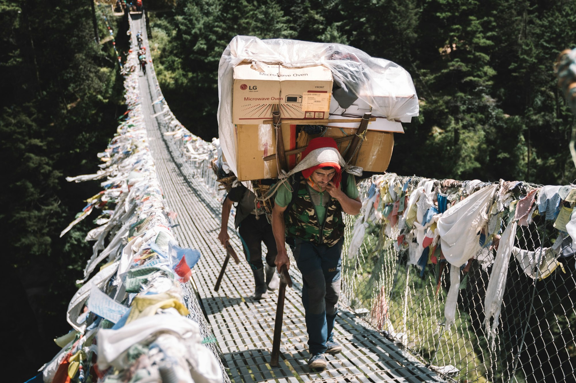 A photo of a porter crossing a bridge with a heavy load