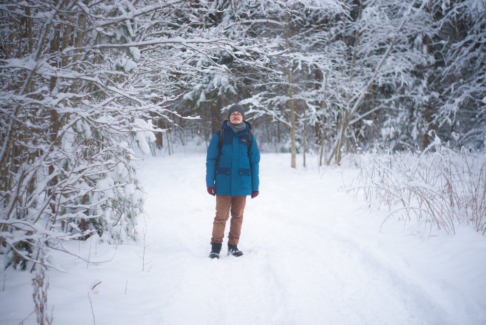 woman in blue coat standing on snow covered ground