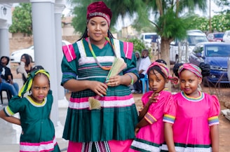 woman in green and red dress standing beside girl in pink dress