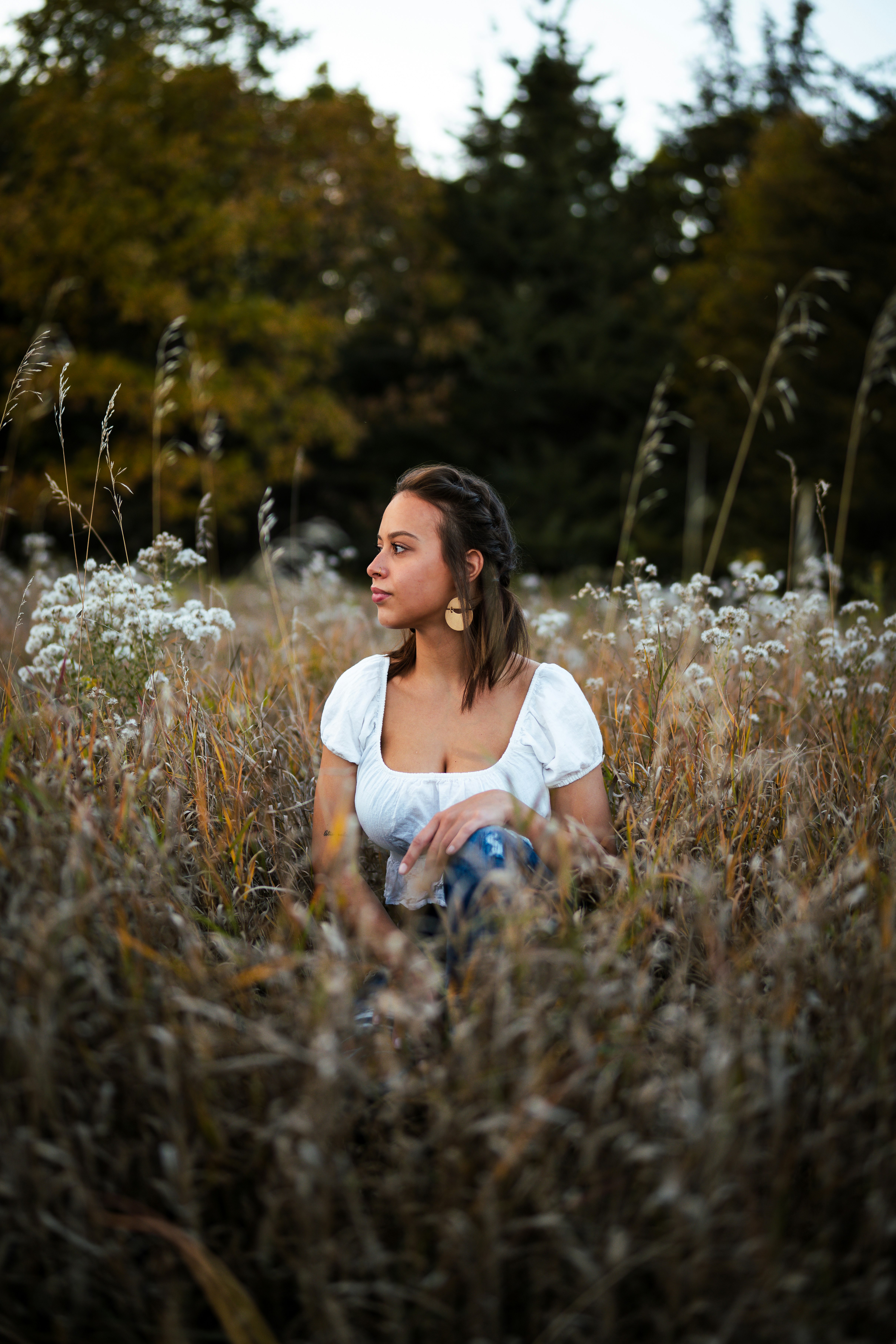 woman in white scoop neck shirt sitting on brown grass field during daytime
