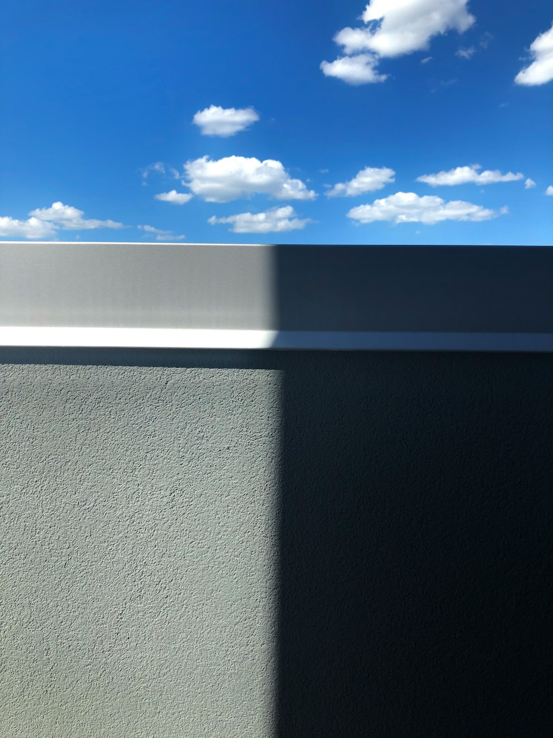 grey concrete wall under blue sky and white clouds during daytime