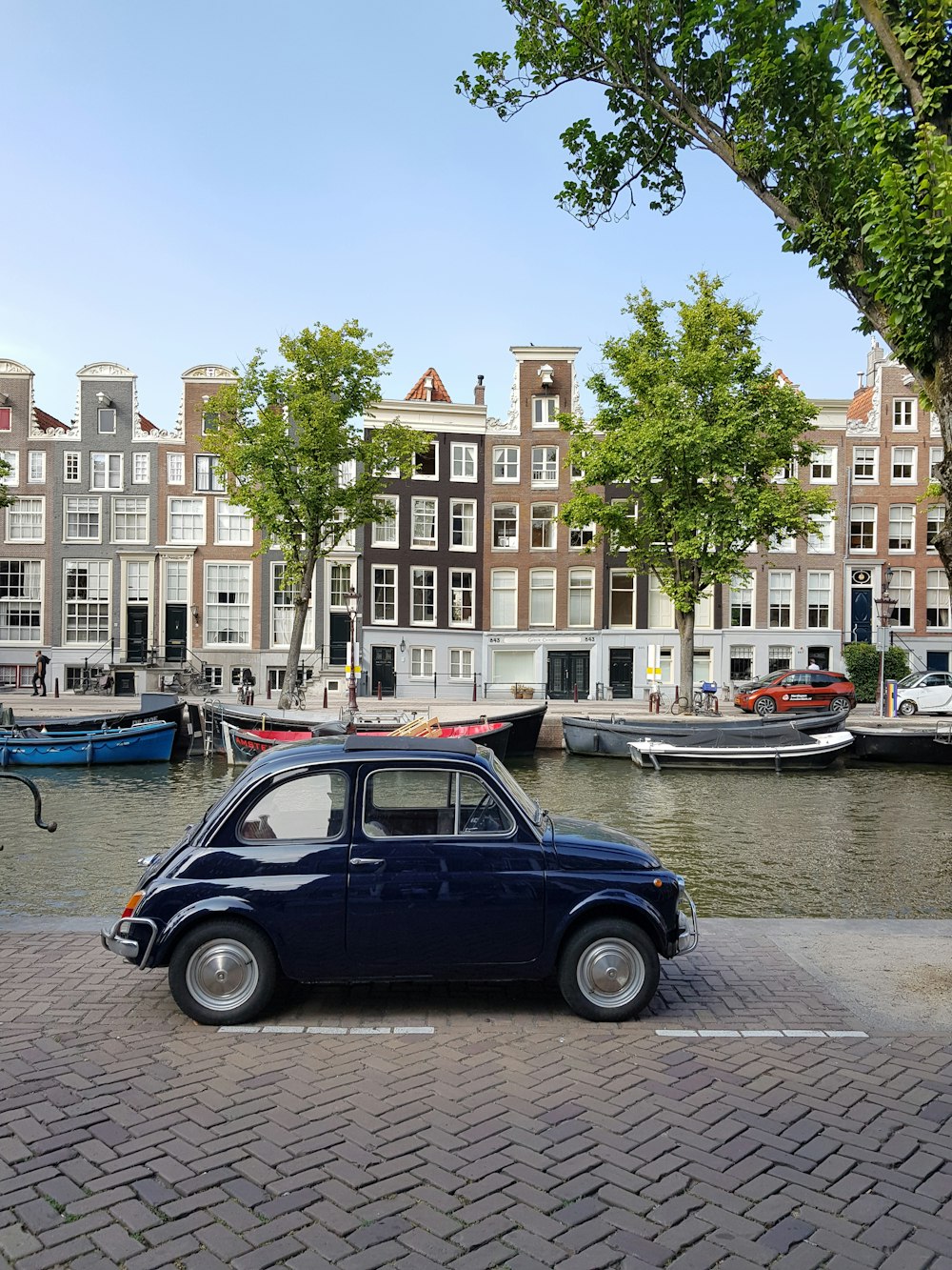 blue sedan parked beside blue and white boat on water during daytime