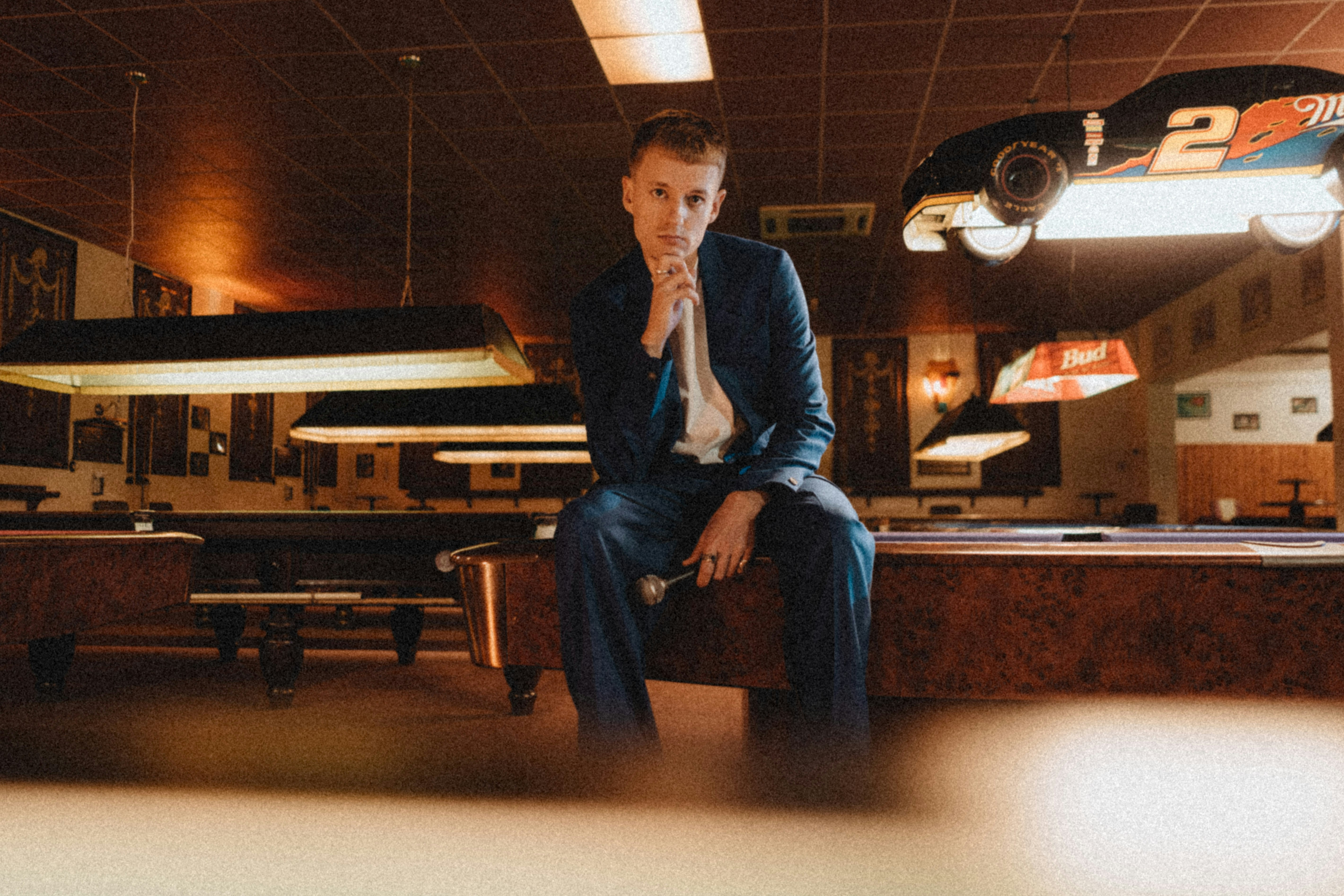 man in blue suit jacket sitting on brown wooden bench