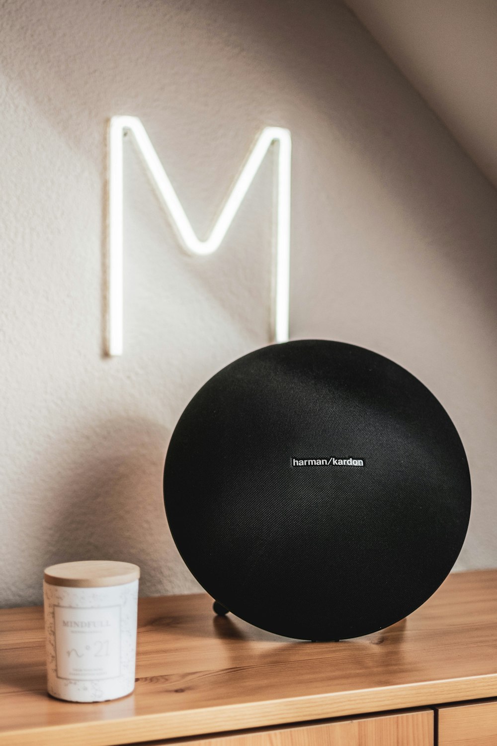 black round speaker beside white plastic cup on brown wooden table