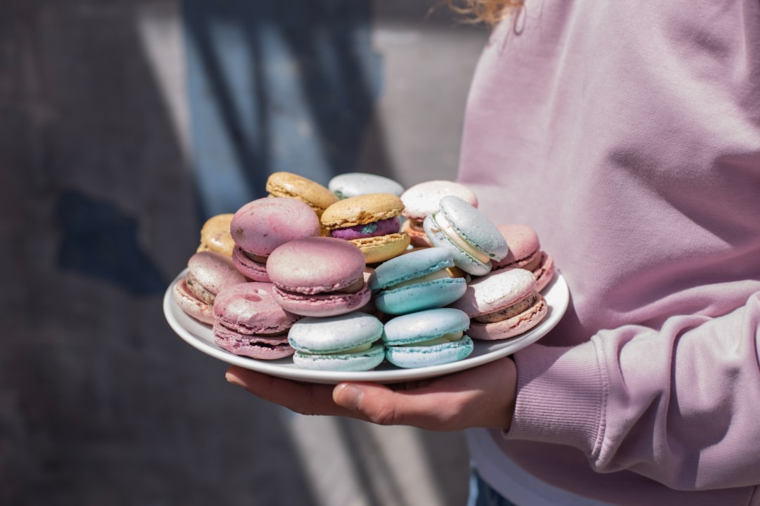 person in pink long sleeve shirt holding pink ceramic bowl with assorted color of candies