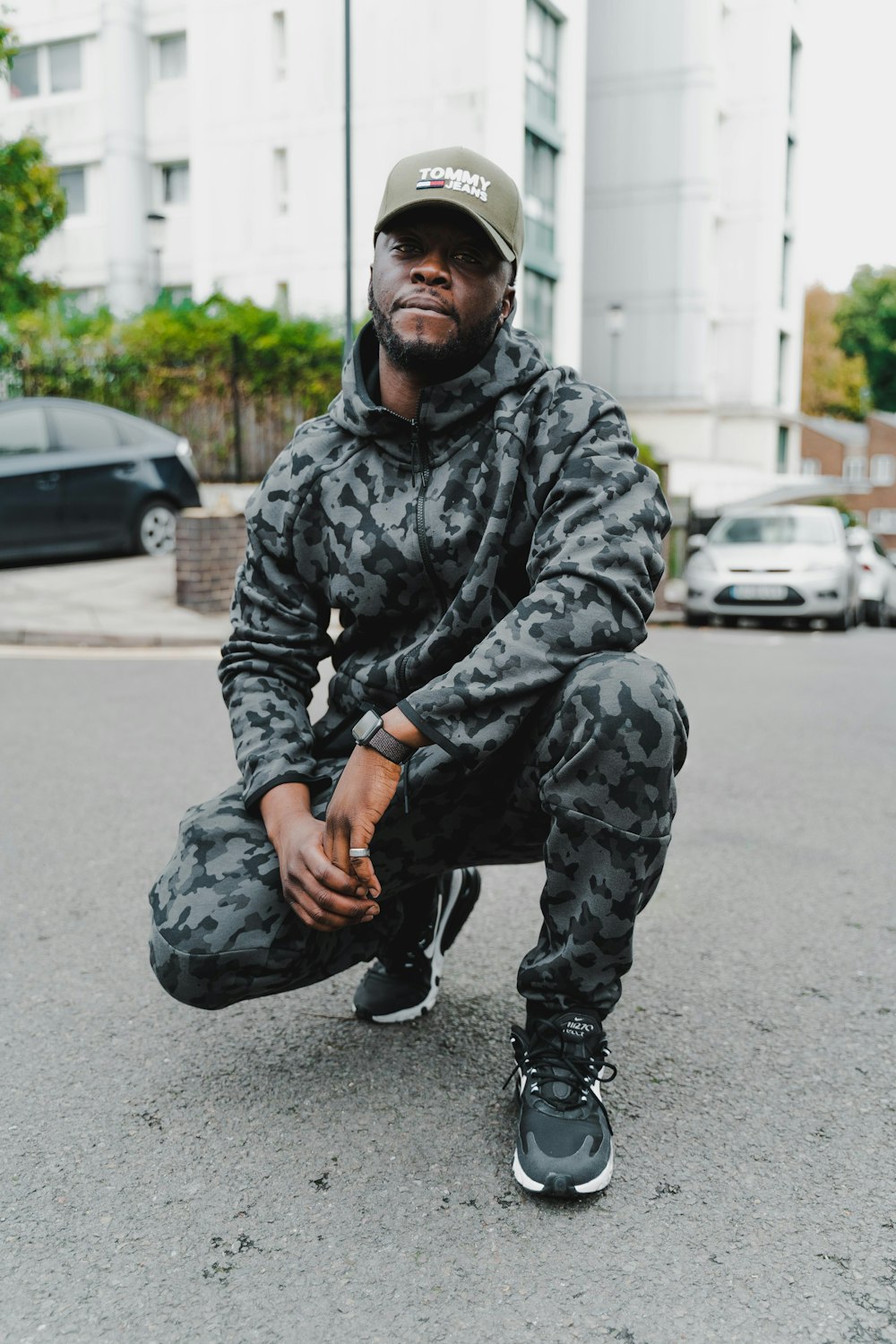 man in camouflage jacket sitting on road during daytime