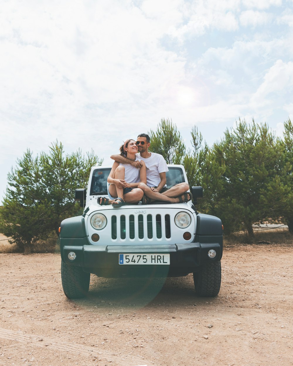 woman in white tank top sitting on black jeep wrangler