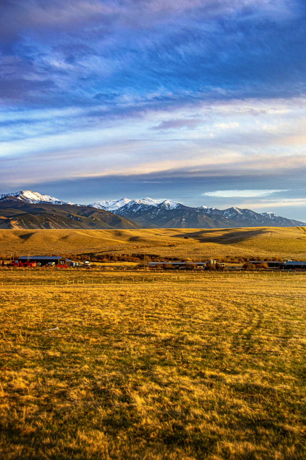 green grass field near mountain under white clouds during daytime