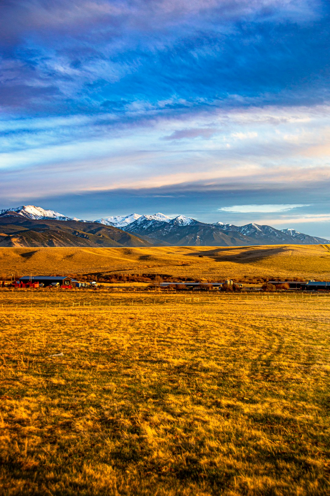 green grass field near mountain under white clouds during daytime