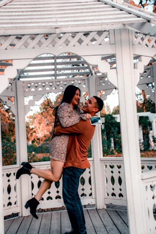 Scott and Flavia sharing a joyful laugh beneath a canopy of leaves during their outdoor ceremony.