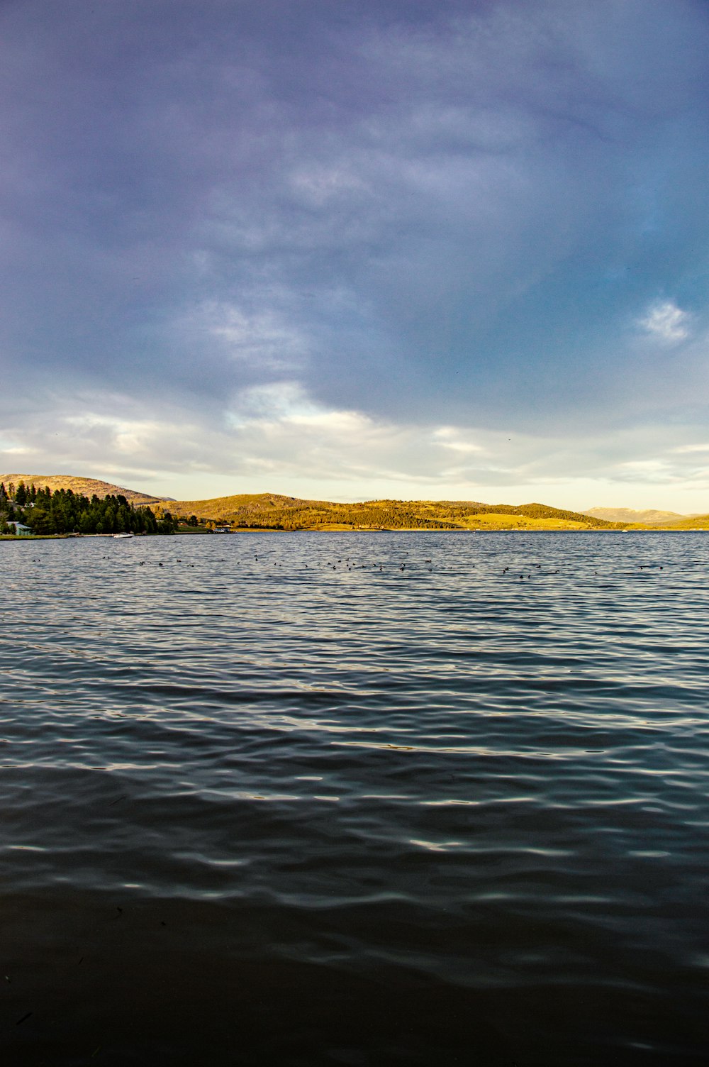 body of water near mountain under blue sky during daytime