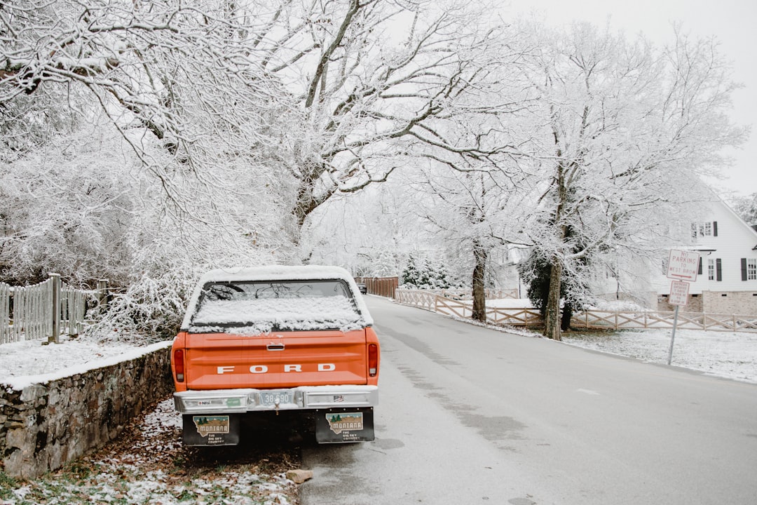 red and white chevrolet truck on snow covered road during daytime