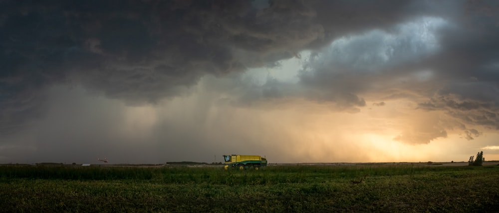 yellow and black bus on green grass field under white clouds