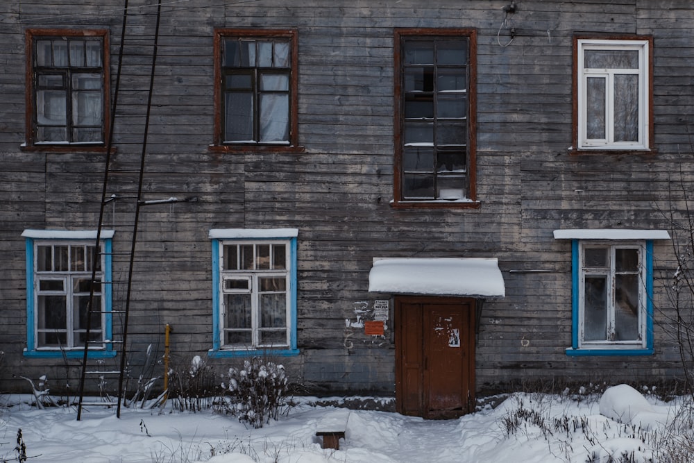 brown brick house with snow covered field