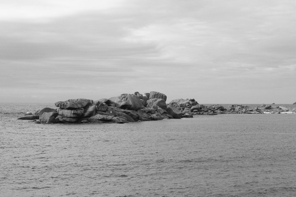 grayscale photo of rock formation on sea