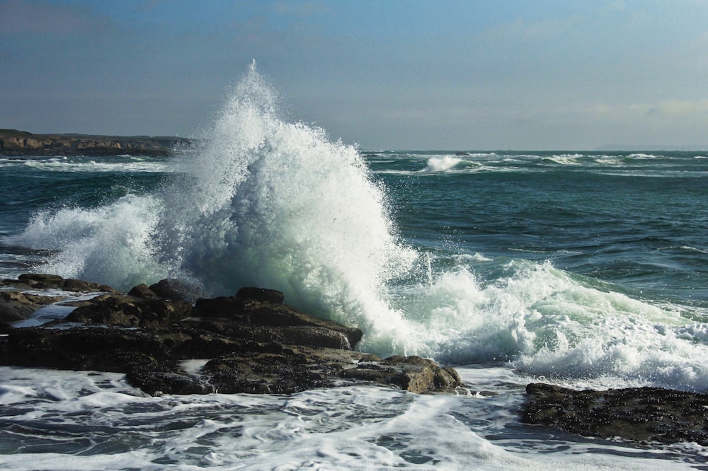 ocean waves crashing on brown rock formation during daytime