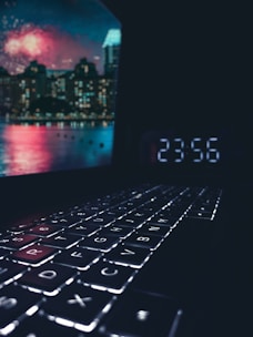 Close-up of hands typing on a laptop keyboard with a modern cityscape blurred in the background.