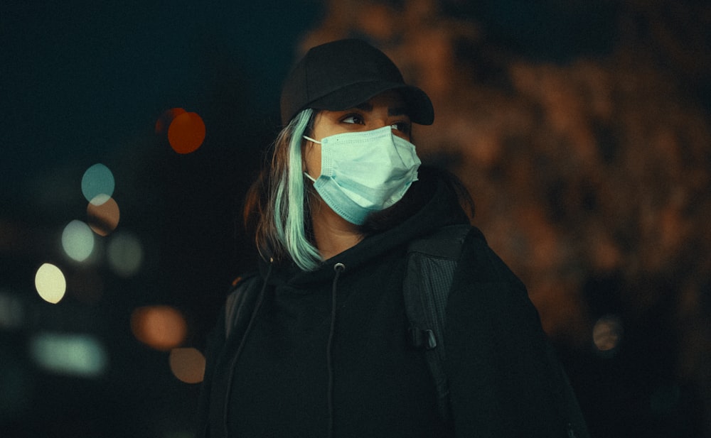 femme en sweat à capuche noir portant un masque blanc