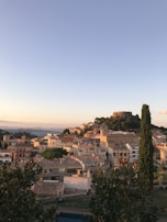 A panoramic view of a charming Spanish town nestled among hills under warm golden light.