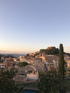 A panoramic view of a charming Spanish town nestled among hills under warm golden light.
