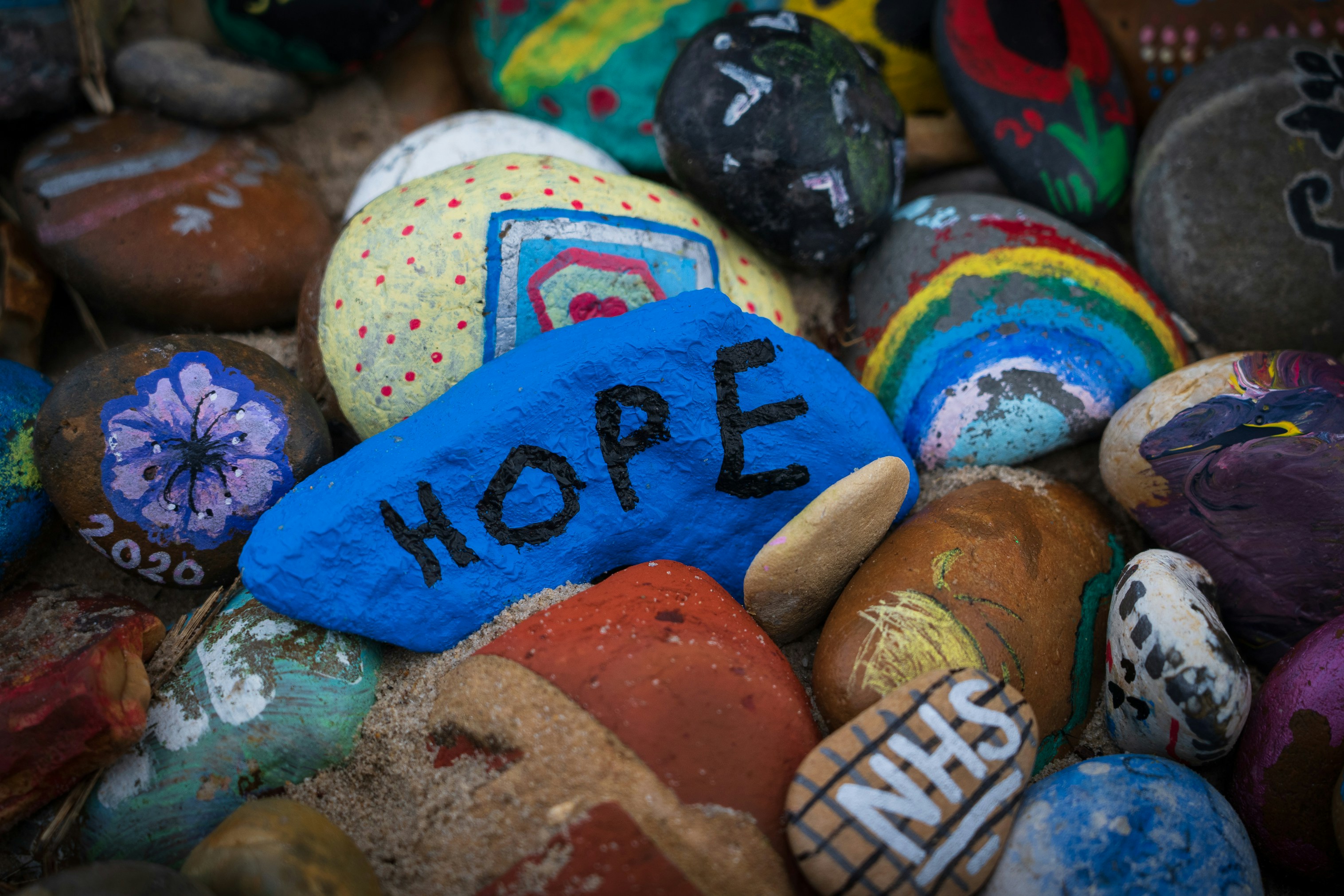 A pebble painted blue, with the word hope written on it in black.