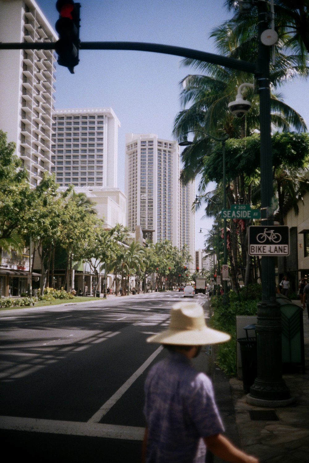 man in white hat walking on sidewalk during daytime