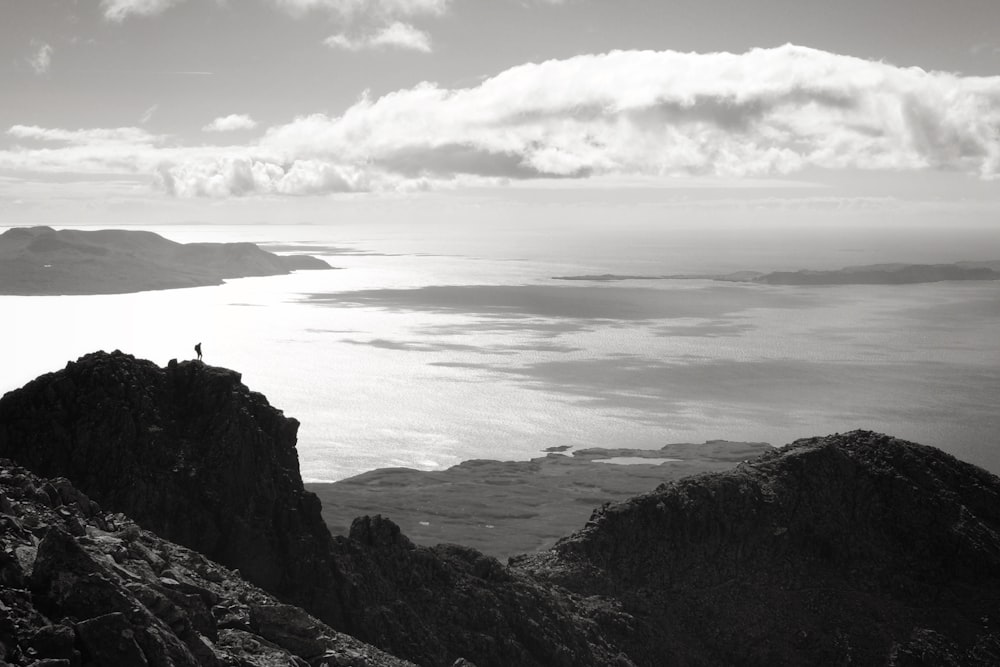 brown rocky mountain beside sea under white clouds during daytime