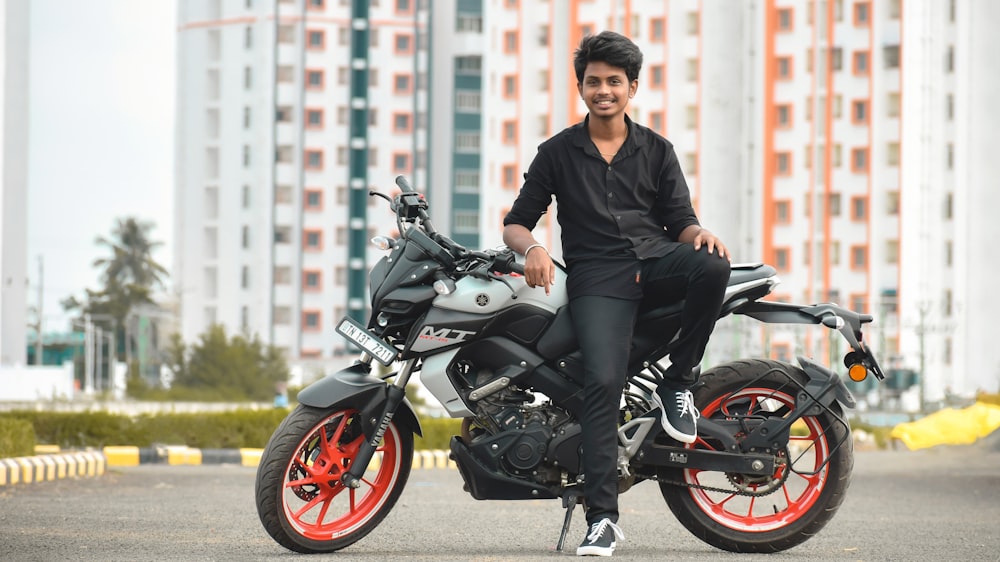 man in black jacket riding black and red motorcycle