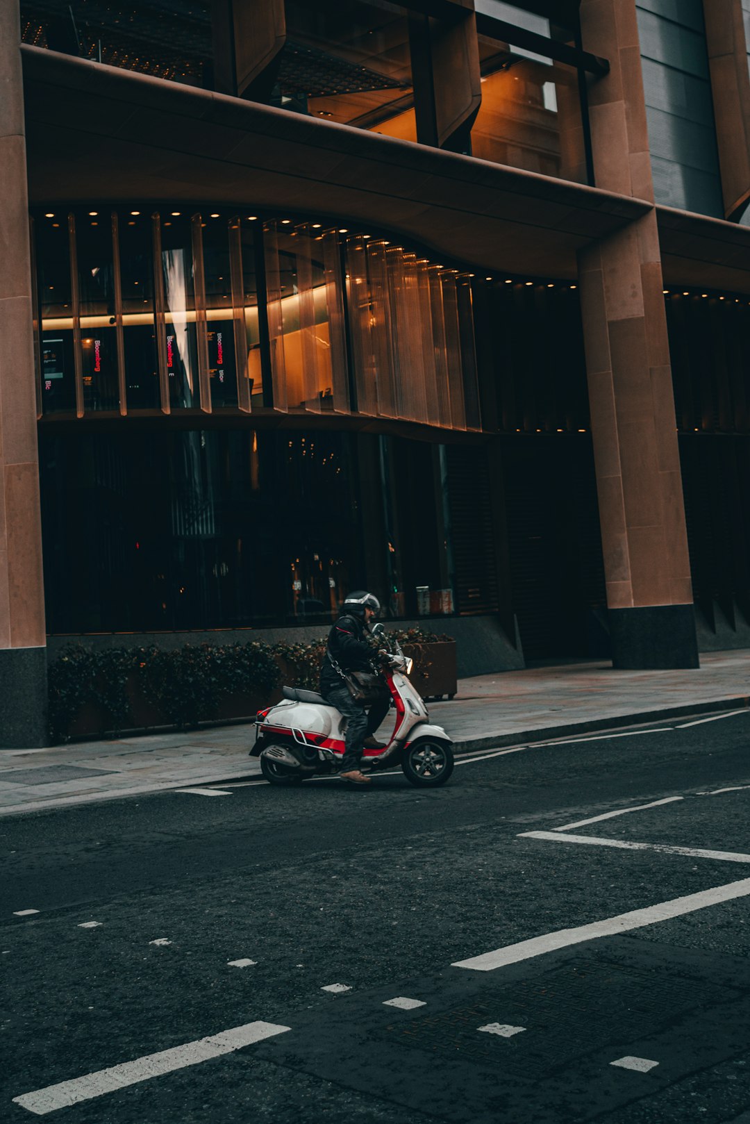 red and black motor scooter parked beside brown wooden building during daytime